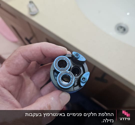 יד מחזיקה חלק פלסטיק ליד כיור בחדר אמבטיה